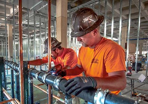 Plumbers installing pipework on site